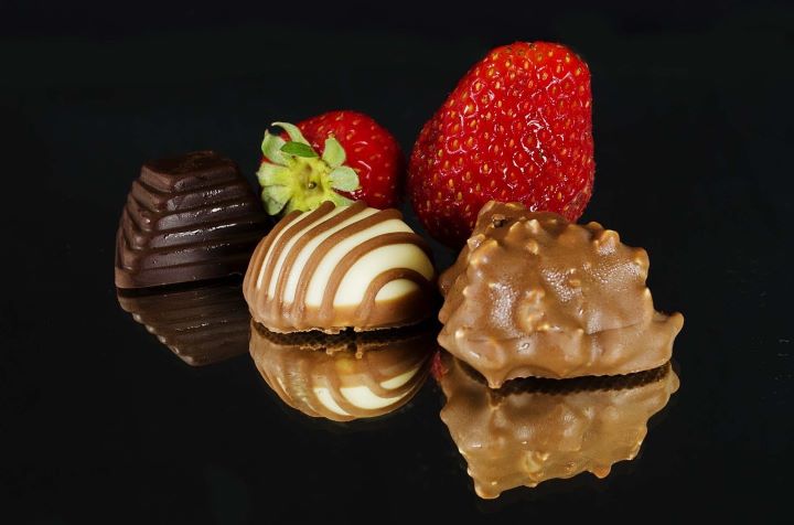 Шоколадные конфеты и клубника на черном фоне